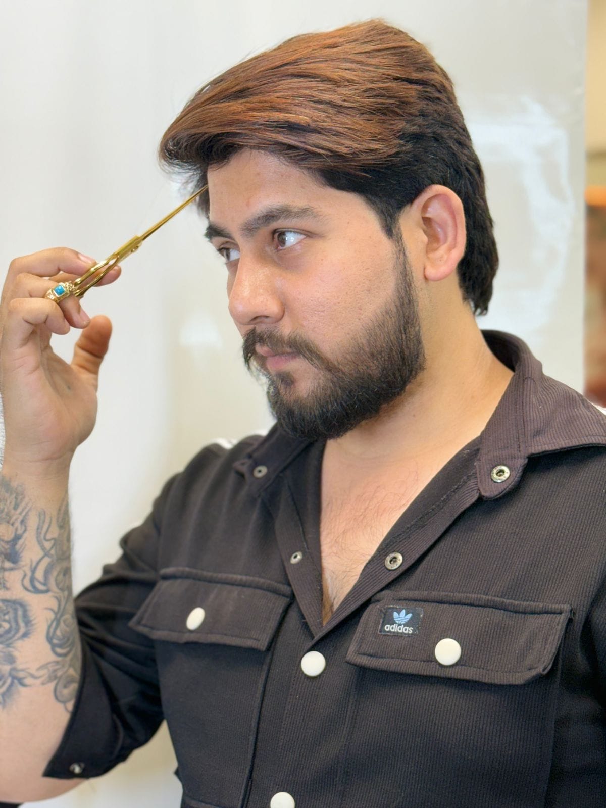 Image of Co-owner of iconic salon, Mr Kartik Sharma, holding a golden scissor