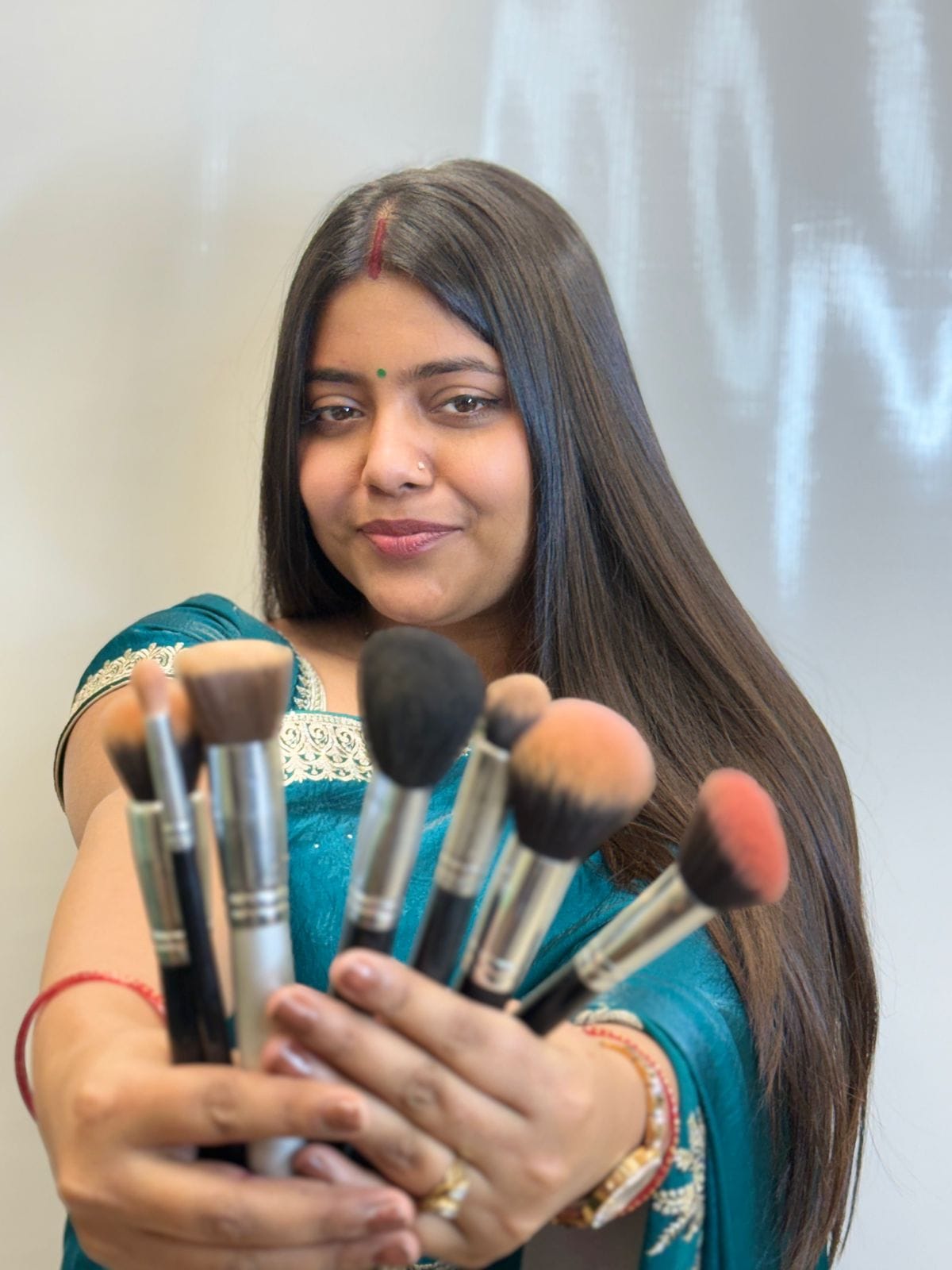 Image of co-owner of Iconik Salon, Mrs Arpita, holding makeup brushes