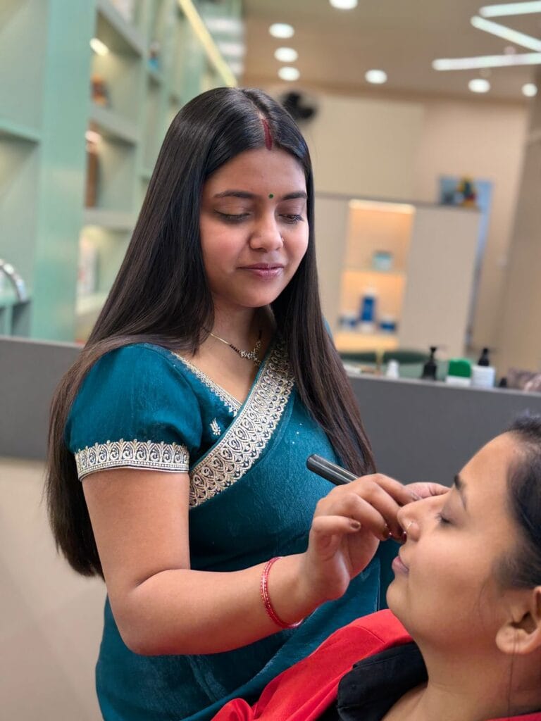 Image of the co-owner of conik Salon, Mrs. Arpita, doing make up of a client and holding a makeup brush in her hand